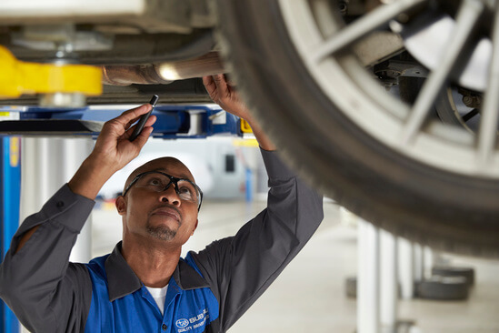 A mechanic checking under a Subaru