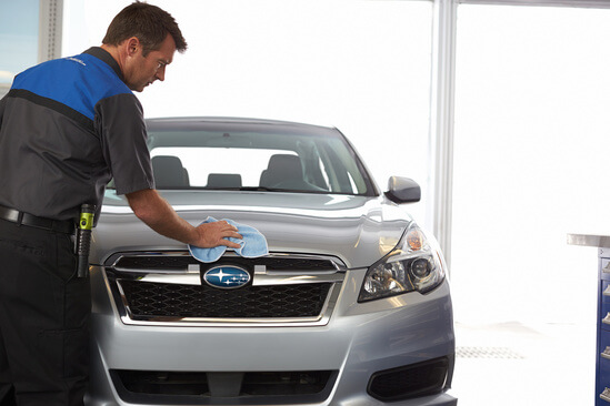 A mechanic wiping off a Subaru