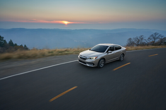 A Silver Subaru Legacy driving at sunset