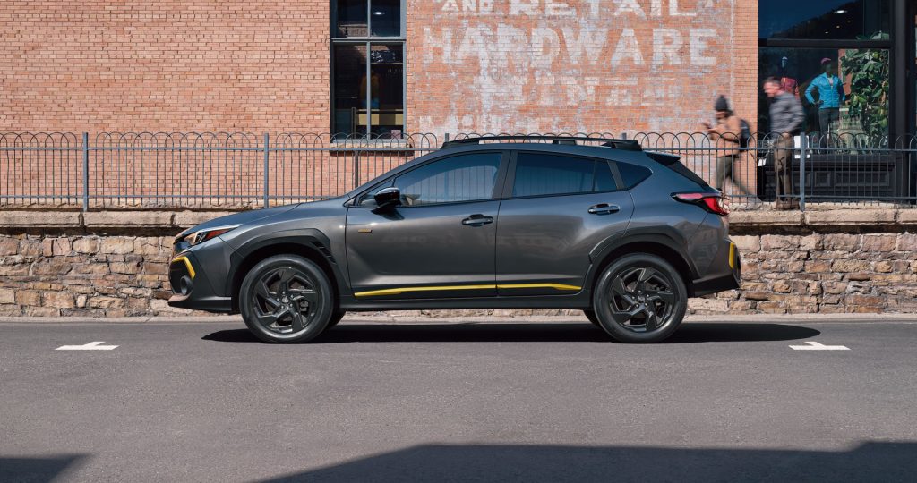 A gray Subaru Crosstrek with yellow accents parked in front of a brick wall.